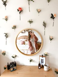 a woman taking a selfie in front of a mirror with flowers on the wall