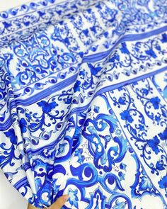 blue and white patterned fabric being held up