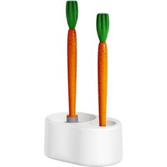 two carrot shaped toothbrushes sitting in a holder on a white surface with green tops