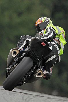 a man riding a motorcycle on top of a race track with trees in the background