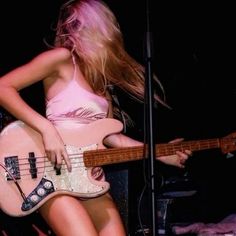 a woman with long blonde hair playing a guitar