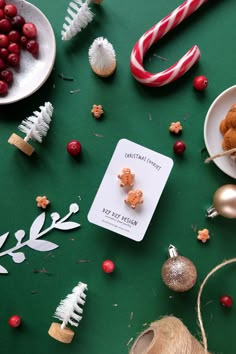 a table topped with christmas treats and candy canes on top of green surface next to other holiday decorations