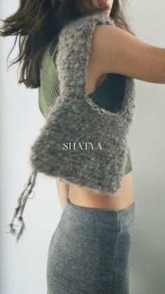 a woman holding onto a gray bag with the word shanta on it's side