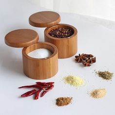 three wooden containers filled with spices on top of a white table next to red chili peppers