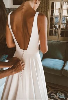 the back of a woman's wedding dress as she stands in front of a couch