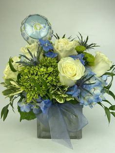 a vase filled with blue and white flowers on top of a table next to a balloon