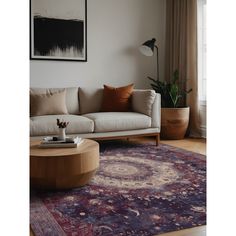 a living room with a couch, coffee table and rug in front of a window