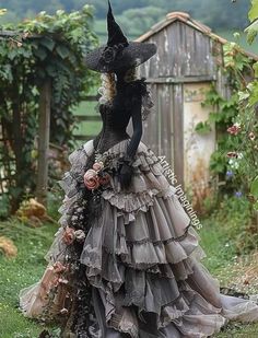 a woman in a black dress and hat with flowers on her head is standing outside