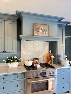 a stove top oven sitting inside of a kitchen next to blue cabinets and counter tops