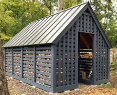 a small shed with a metal roof in the middle of some trees and leaves on the ground