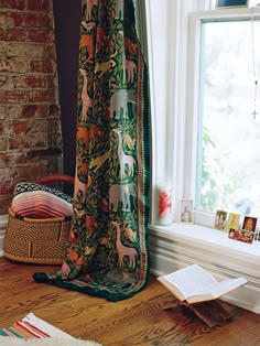 an open book sitting on top of a wooden floor next to a window