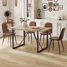 a dining room table with four chairs and a vase on the side, in front of a white wall