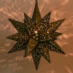 a star shaped light hanging from the ceiling with clouds in the backgroung