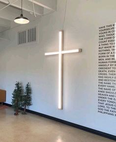 a large cross hanging from the side of a wall next to a small christmas tree