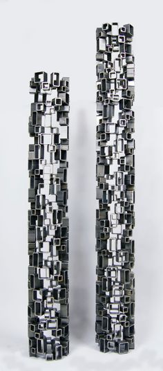 two black and white vases sitting side by side on a white surface, one is made out of metal squares