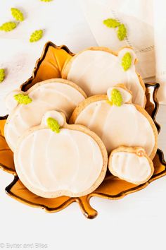 cookies decorated with white icing and green leaves on a yellow plate next to a napkin