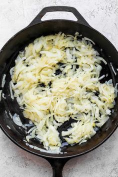 an iron skillet filled with sauteed onions on top of a white counter