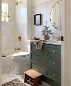 a white toilet sitting next to a bath tub in a bathroom under a mirror above a sink