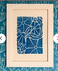 a blue and white flower print on a wall next to two framed pictures with the same design