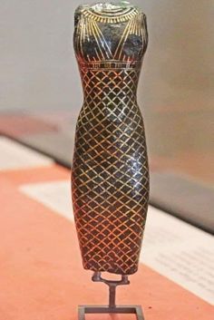 an ancient vase is on display in a museum exhibit, it appears to have been made from wood and metal