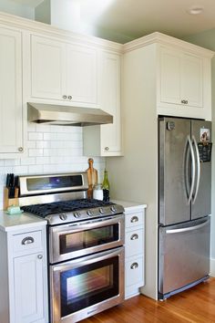 a kitchen with white cabinets and stainless steel appliances