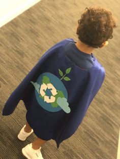 a little boy in a blue shirt and white tennis shoes looking at something on the floor