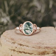 a green and white marble ring on top of a stone slab with leaves around it