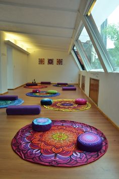 yoga mats are lined up on the floor in front of an open room with large windows