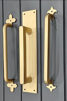 two brass door handles on the side of a gray metal wall with black and white stripes