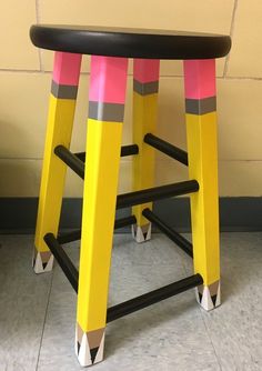 two yellow and pink stools sitting in front of a wall