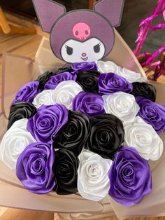 a bouquet of purple and white roses in a box with a cat decoration on top