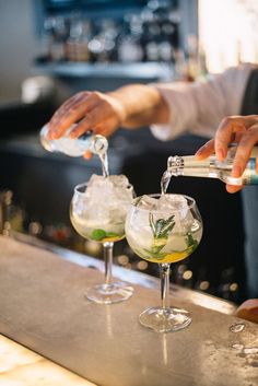 someone pouring drinks into glasses on a bar