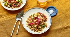 two plates of food on a table next to silverware and glasses with beer in them