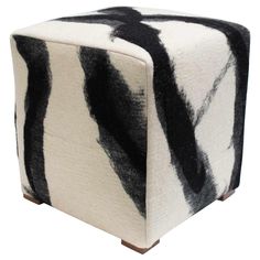 a black and white striped ottoman sitting on top of a wooden block with wood legs