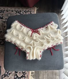 a piece of knitted clothing sitting on top of a rug next to a radiator