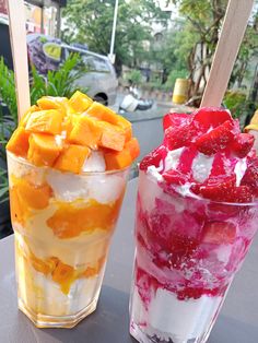 two glasses filled with ice cream and fruit on top of a table next to each other