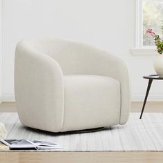 a white chair sitting on top of a wooden floor next to a vase filled with flowers