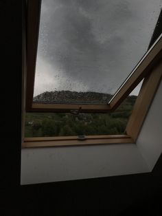 a window with rain drops on it in the middle of a room that has a skylight