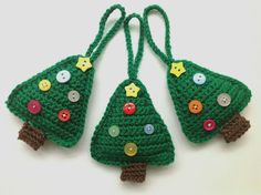 three crocheted christmas tree ornaments with buttons on each ornament are shown