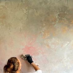 a woman painting a wall with pink paint