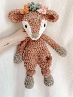 a crocheted stuffed animal is being held by a person's hand on a white sheet