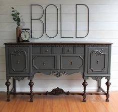 an old dresser is painted gray and has ornate carvings on the top, along with a clock