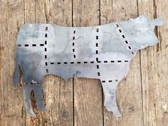 a metal cow cut out on top of a wooden floor with holes in it's back