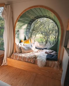 a bedroom with an arched window and wooden flooring is shown in this image, the bed has pillows on it