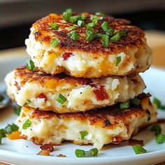 three crab cakes stacked on top of each other with green onions and scallions