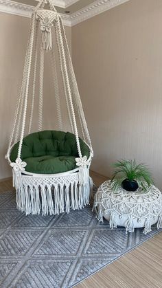 a white hanging chair with green cushions and a small table on the floor next to it