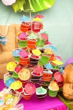 a table topped with lots of cupcakes covered in umbrellas and muffin cups