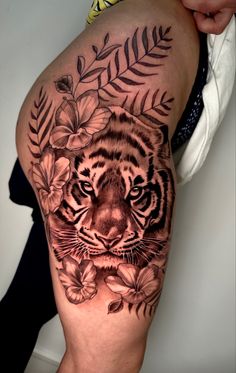 a close up of a person's leg with a tiger tattoo on the thigh