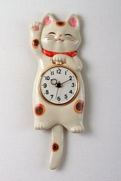 a cat clock hanging on the wall with it's paws up in the air