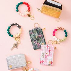 several purses and key chains laid out on a pink surface